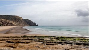 A coastal beach with a rocky foreground, a sandy shore, and a cliff in the background. - Charming Villa with Heated Pool & Large Garden near Sandy Beach, Hiking and Golf (Praia da Luz)