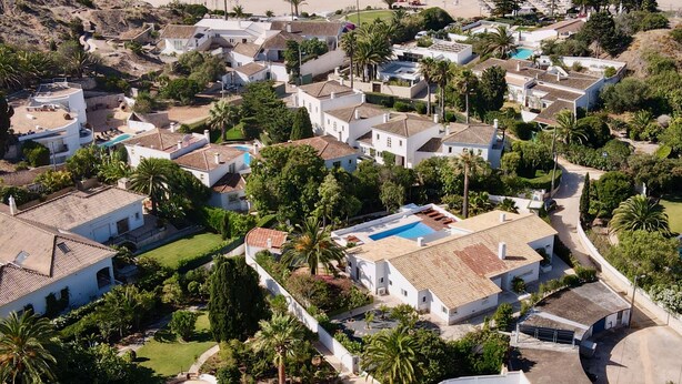 An aerial view of a coastal residential area with houses, a beach, and a swimming pool. - Charming Villa with Heated Pool & Large Garden near Sandy Beach, Hiking and Golf (Praia da Luz)