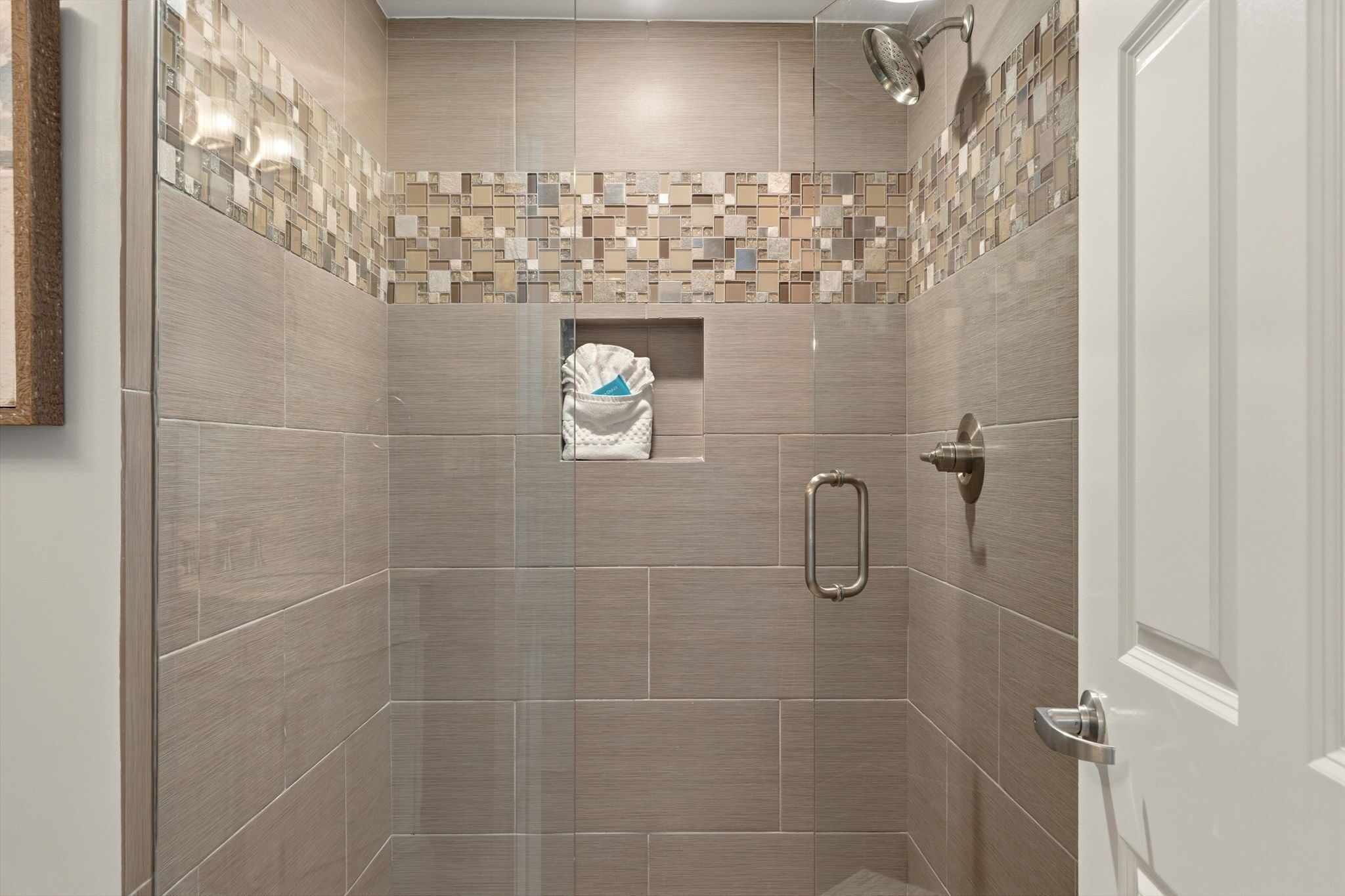 Une douche avec un mur carrelé, un porte-serviettes et un pommeau de douche.