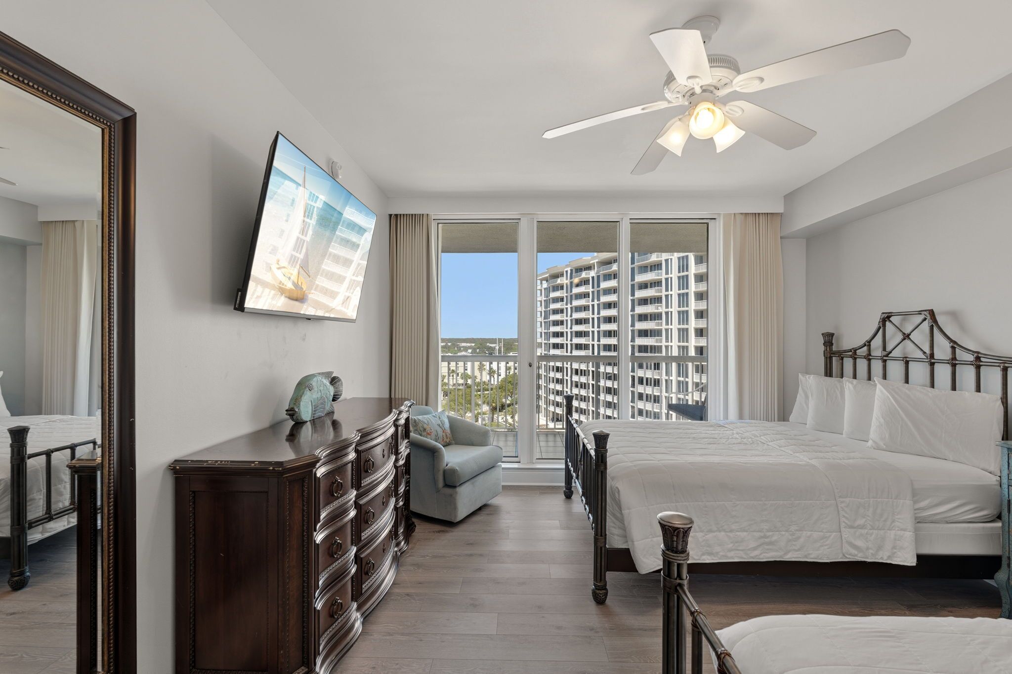 A bedroom with a bed, dresser, chair, and a ceiling fan.