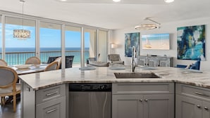 Uma cozinha moderna com uma ilha grande, uma área de jantar com cadeiras e vista para o oceano.