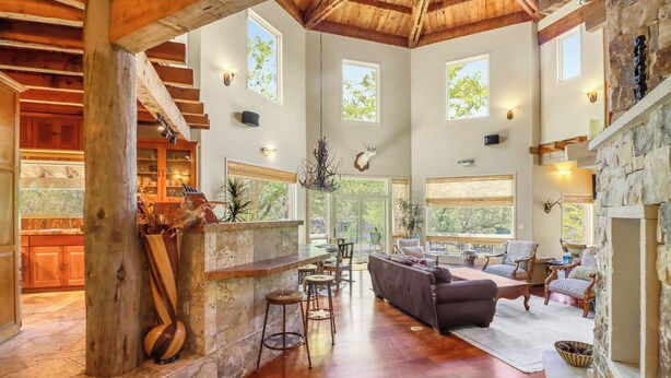 A spacious interior with a wooden ceiling, stone fireplace, and large windows.