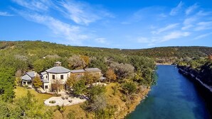 A large house with a circular driveway and a river in the background.