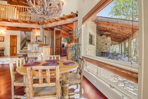 A spacious dining area with a wooden table and chairs, a stone wall, and a view of the outdoors.