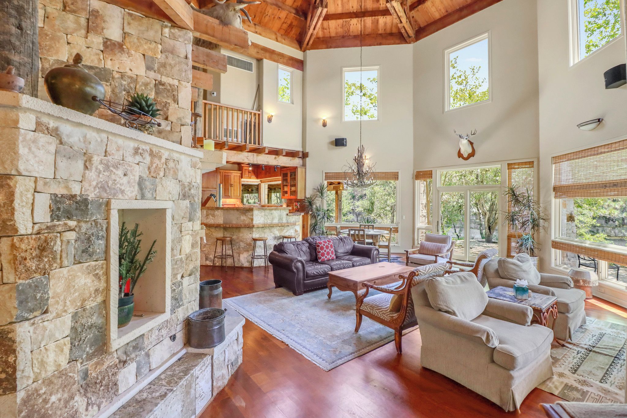 A spacious living area with a stone fireplace, wooden ceiling, and large windows.