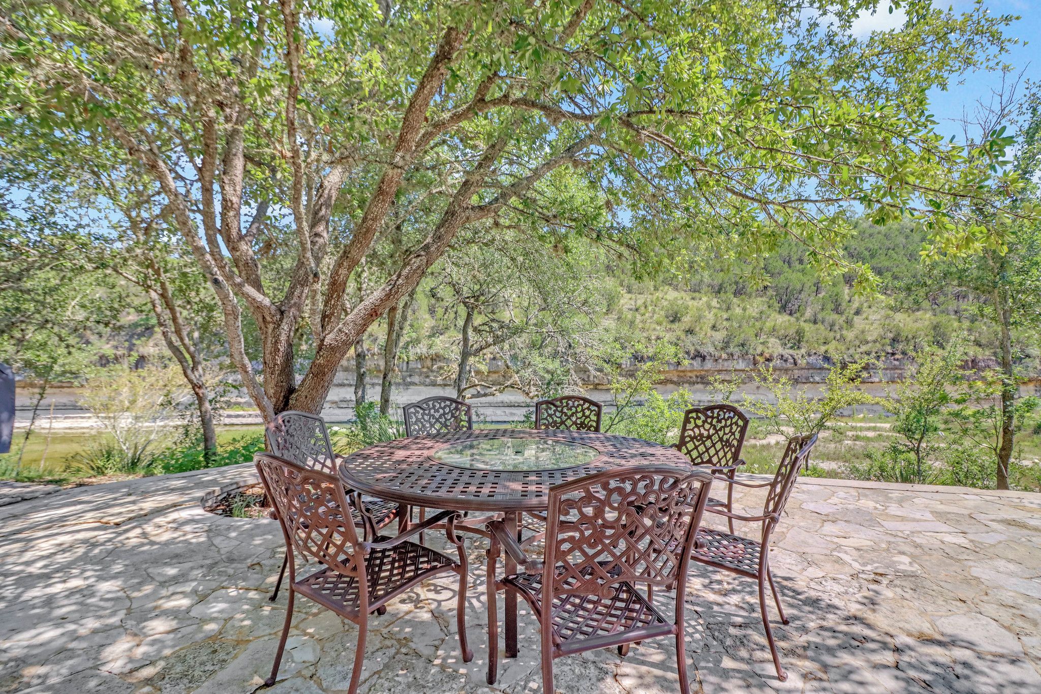 Un espace de restauration en plein air avec une table ronde et des chaises, entouré d’arbres.
