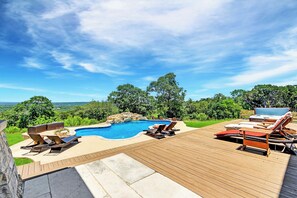 Una terraza de madera con piscina, sillas de descanso y un jacuzzi.