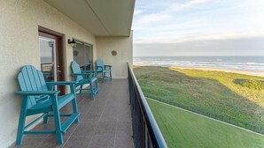 A balcony with teal Adirondack chairs, a door, and a view of the ocean. - Saida I 602 - Beachfront Condo, Private Balcony, Tennis Courts, Oceanfront Swimming Pools, Hot Tubs (South Padre Island)