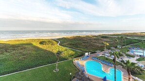 A resort with a swimming pool, lounge chairs, and a view of the ocean. - Saida I 602 - Beachfront Condo, Private Balcony, Tennis Courts, Oceanfront Swimming Pools, Hot Tubs (South Padre Island)
