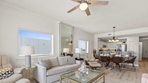 A spacious living room with a glass coffee table, a sofa, and a dining area with chairs and a table. - Gulf Dunes 617: Sand Dollar Daze - Marvelous 3 bed, 3 bath unit! A must see! (Fort Walton Beach)