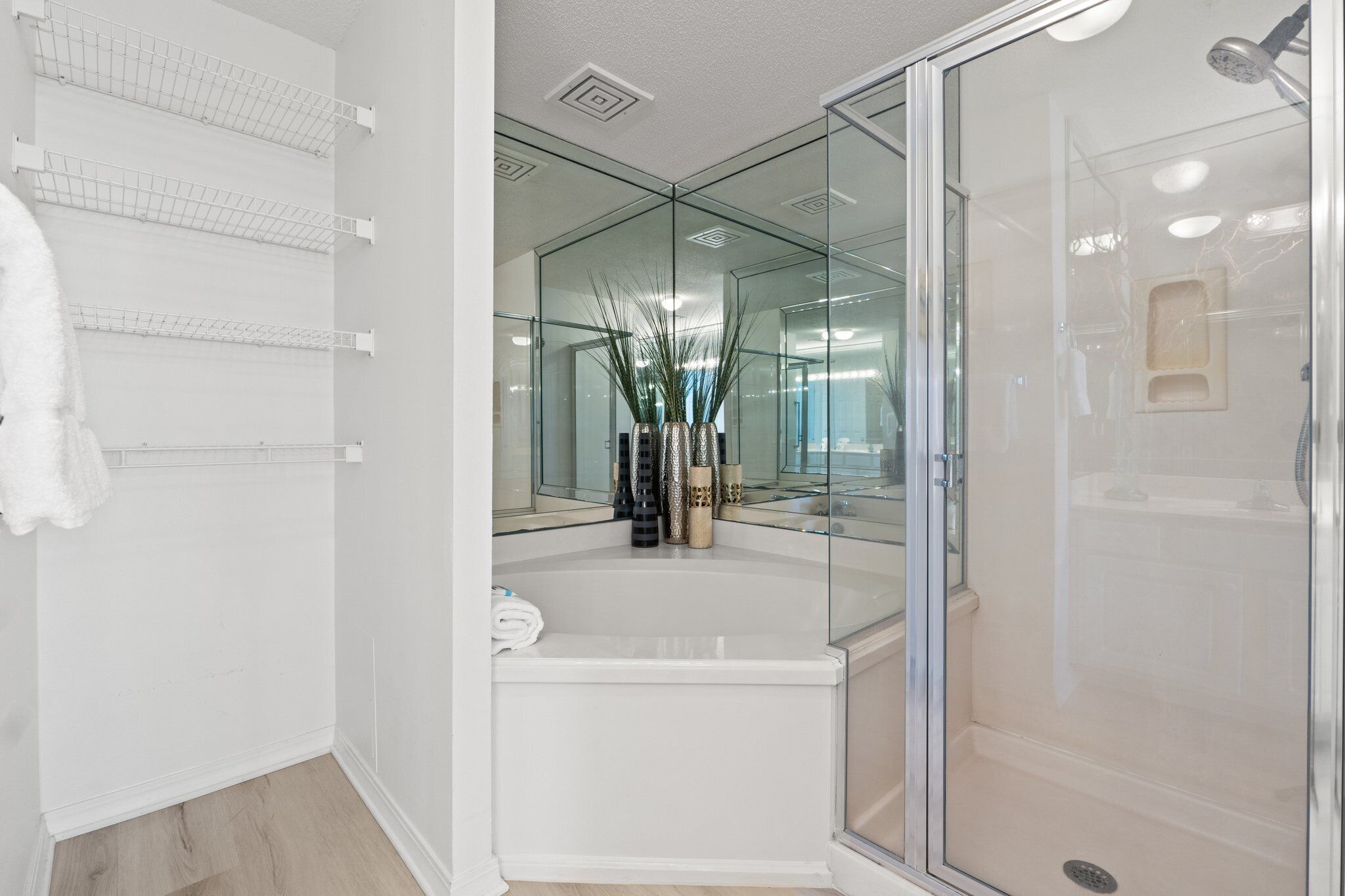Un baño moderno con ducha de vidrio, una bañera blanca y un estante con toallas.