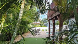 A pool area with a small water feature, surrounded by palm trees and a covered seating area.