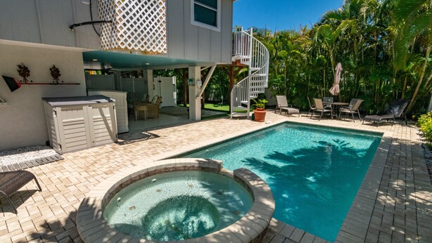 A swimming pool with a hot tub, outdoor seating, and a spiral staircase leading to a second level.