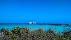 A pier extending into turquoise waters with a building at the end.