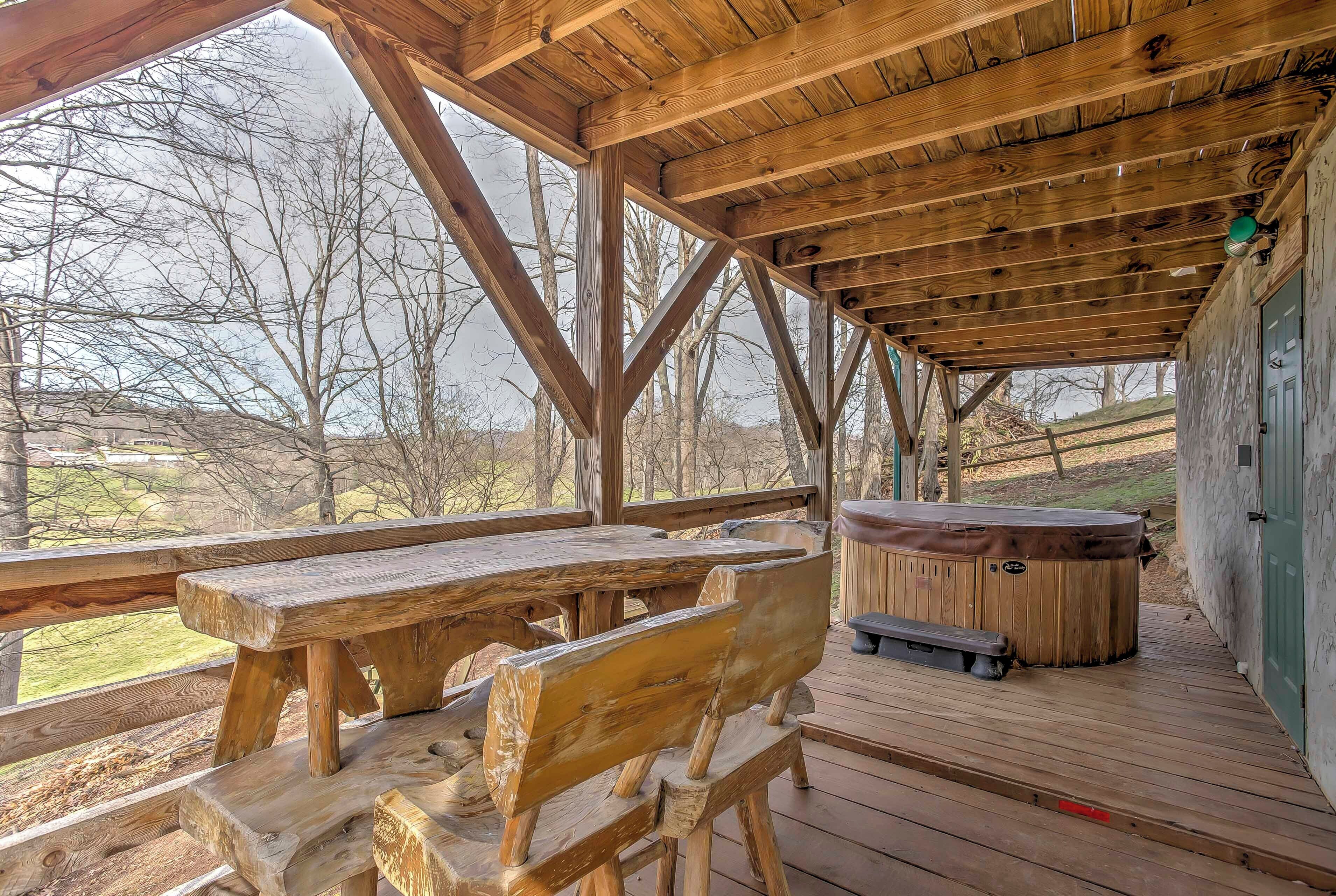 Une terrasse en bois avec un jacuzzi et des tables de pique-nique.