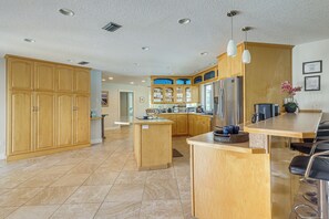Una cocina amplia con armarios de madera, una isla central y un refrigerador de acero inoxidable.