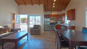 A spacious living area with a wooden ceiling, a dining table, and a kitchen with wooden cabinets. - Fantastic upstairs unit just one house from the warm sand (Newport Beach)