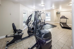 A home gym with an elliptical, a weight machine, a treadmill, and a stationary bike.