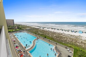 A pool with a view of the beach and ocean, a building with balconies, and a clear sky. - WE 507: Tropical Tides - The Gulf is Calling, Gorgeous Beachfront Views Await (Fort Walton Beach)