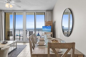 Un comedor con vistas al océano, un ventilador de techo y un espejo grande.