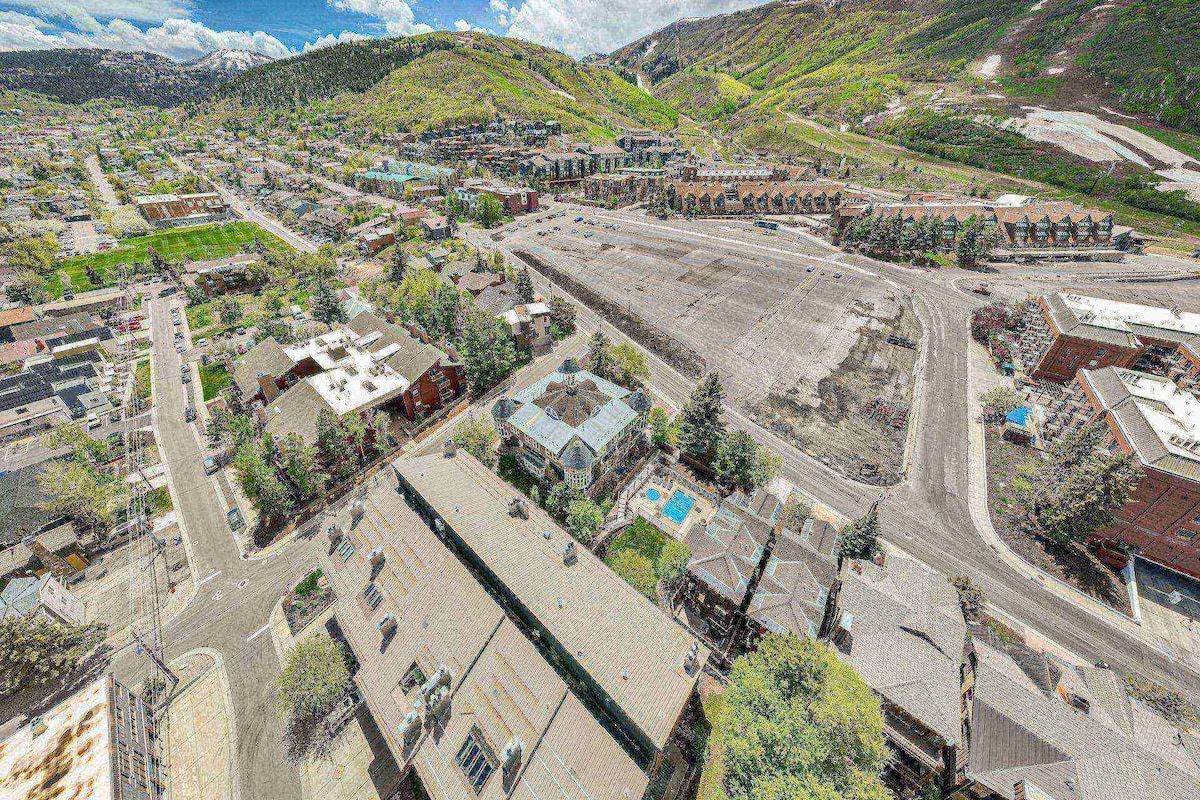 A town with a mix of residential and commercial buildings, a central road, and surrounding hills.