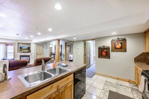 Una cucina moderna con lavastoviglie, bacinella doppia e pensili in legno.