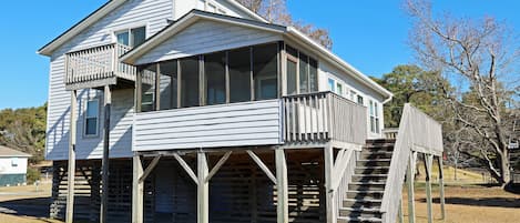 Une maison en bois à deux étages, dotée d’un balcon et d’une véranda.
