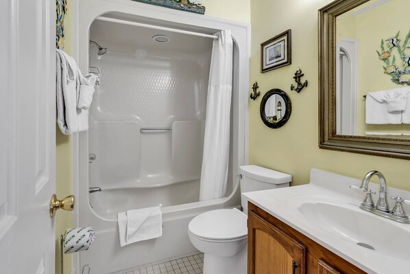 A bathroom with a bathtub, toilet, sink, and a mirror.