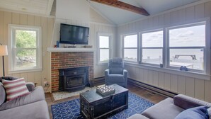 Ein gemütliches Wohnzimmer mit Kamin, Fernseher und Blick auf das Wasser.