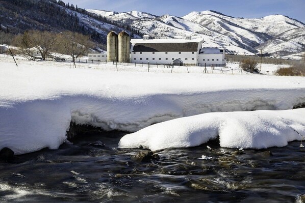 A snow-covered landscape with a building featuring two silos and a barn.