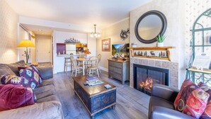 Una sala de estar con chimenea, un comedor y una cocina visibles a través de un umbral abierto.