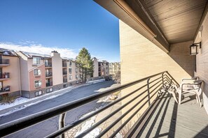 A residential building with a balcony, a clear view of the street, and a snow-covered ground.