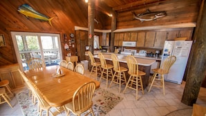 A wooden interior with a dining area, kitchen, and large windows. - WH1091- Oceanfront-  6 BRs, Cargo Lift, Great Ocean Views Dog Friendly! (Corolla)
