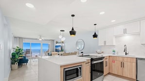 Een moderne keuken met een centraal eiland, een inbouwoven en een magnetron.