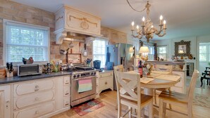 A kitchen with a brick wall, wooden cabinets, a stove, and a chandelier. - 7 Mi to the Biltmore: 'Le Canard' Cottage w/ Porch (Arden)