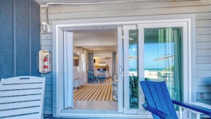 A covered outdoor area with a sliding glass door leading to a dining area with a table and chairs.