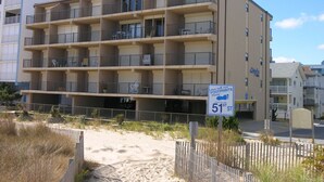 Een hotel met meerdere verdiepingen en balkons, met een zandstrand ervoor, en een bord met het adres 51st Street.