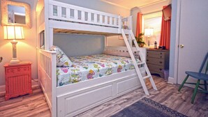 Een stapelbed met een ladder, een bureau met lades, een stoel, een spiegel en een lamp.