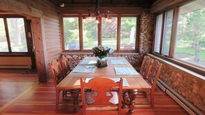 Enjoy meals in this elegant dining area with a long table for six, surrounded by comfortable chairs and a beautiful garden view.
