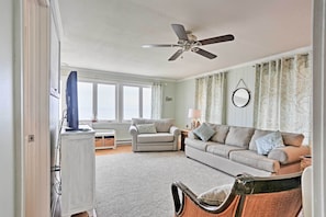 Relax in this spacious living room with two sofas, a coffee table, and a television on a stand.