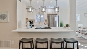 A modern kitchen with a central island, bar stools, pendant lighting, and stainless steel appliances. - 2311 Racquet Club: 3BR 2 BA Villa. Community Pool and Clay Tennis, Free Bikes (Hilton Head Island)