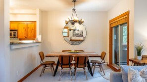 A dining area with a wooden table, six chairs, and a chandelier.