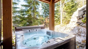 Een hottub onder een houten pergola, met uitzicht op een bos.
