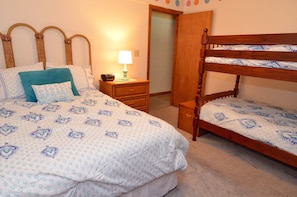 Un dormitorio con una cama doble, una mesita de noche, una lámpara y un banco de madera.