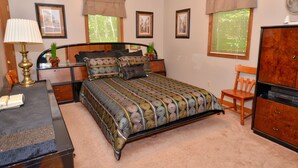 A bedroom with a bed, bedside tables, a dresser, a lamp, and framed pictures on the walls.