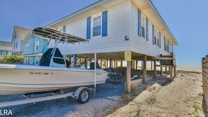 A house with a covered porch, a boat named 'Live Water' on a trailer, and a sandy beach in the background. - The Choice: Oceanfront Comfort in Surf City (Surf City)