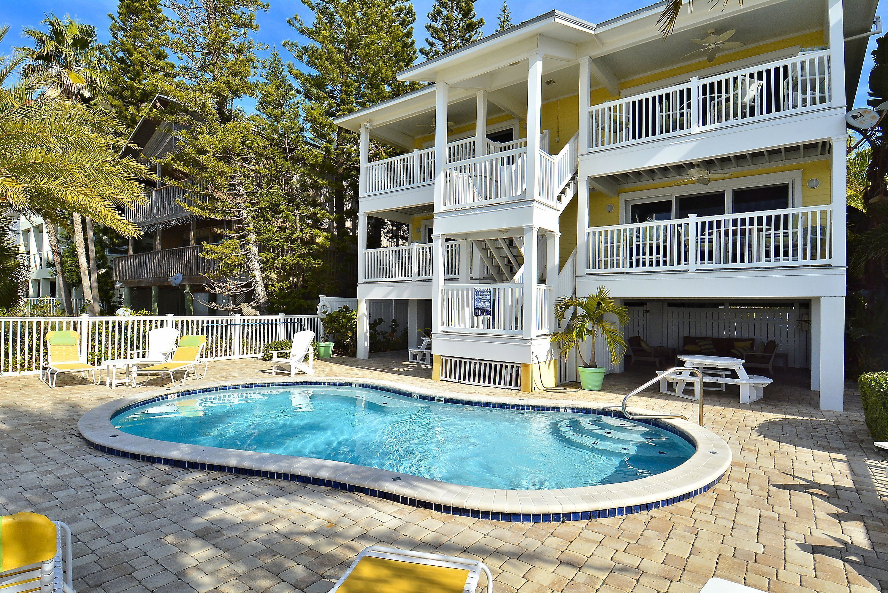 A two-story building with a pool, outdoor seating, and a fenced patio area.