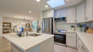 A modern kitchen with white cabinets, stainless steel appliances, and a central island.