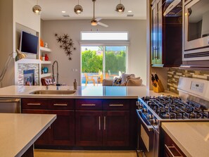 A modern kitchen with dark wood cabinets, a stainless steel range, and a large window overlooking a patio.