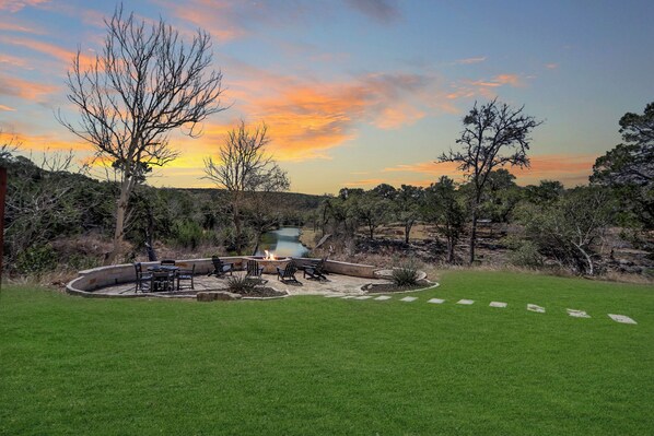 A backyard with a fire pit, seating, and a pond.